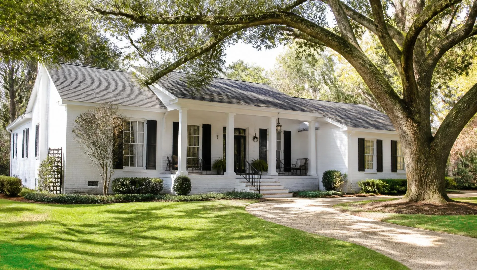 Southern home with a covered front porch shaded by oak trees